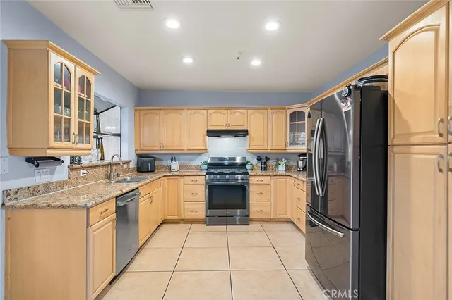 a kitchen with stainless steel appliances granite countertop a refrigerator and a stove top oven