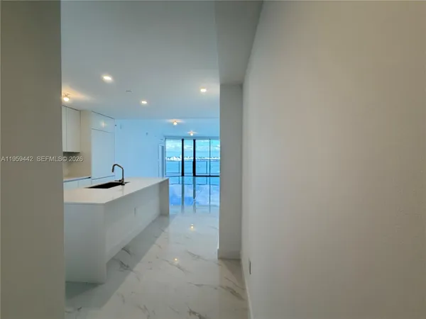 a large white kitchen with a sink and dishwasher a refrigerator with white walls