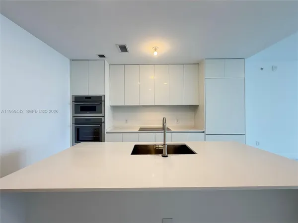 a kitchen with a refrigerator and white countertops