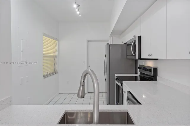 a kitchen with stainless steel appliances granite countertop a sink and a refrigerator