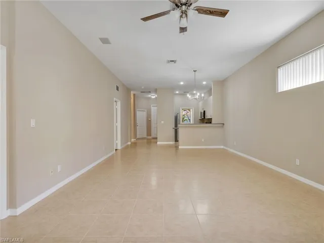 an empty room with a kitchen and a chandelier fan