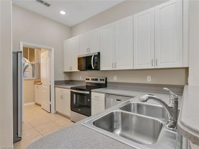 a kitchen with white cabinets and stainless steel appliances