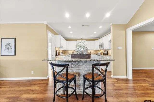 a kitchen with stainless steel appliances granite countertop a kitchen island a stove a cabinets a dining table and chairs