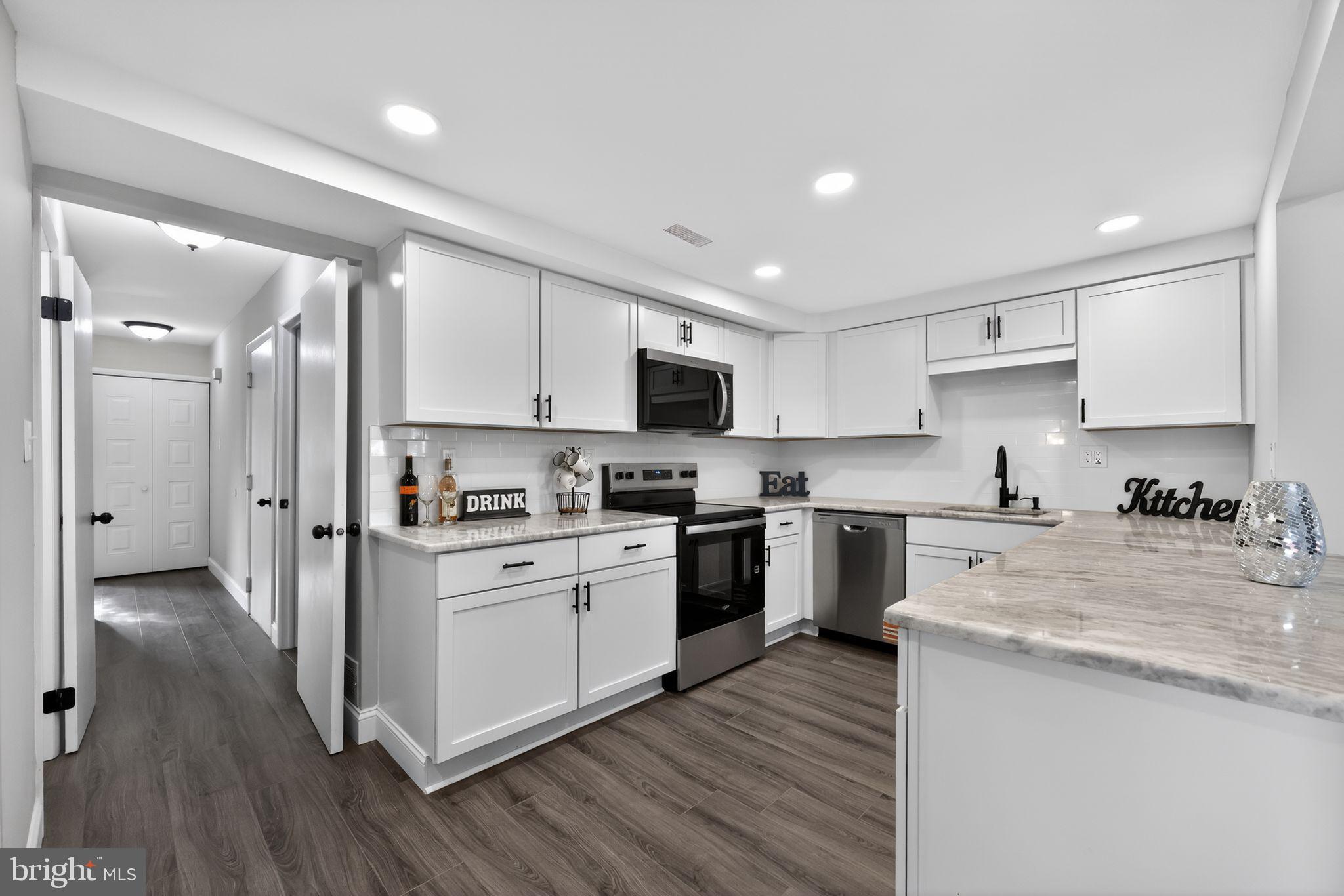 55 Adams Street Swedesboro, NJ 08085 - Photo 7 of 30 a kitchen with stainless steel appliances granite countertop a stove top oven a sink dishwasher and a refrigerator with wooden floor