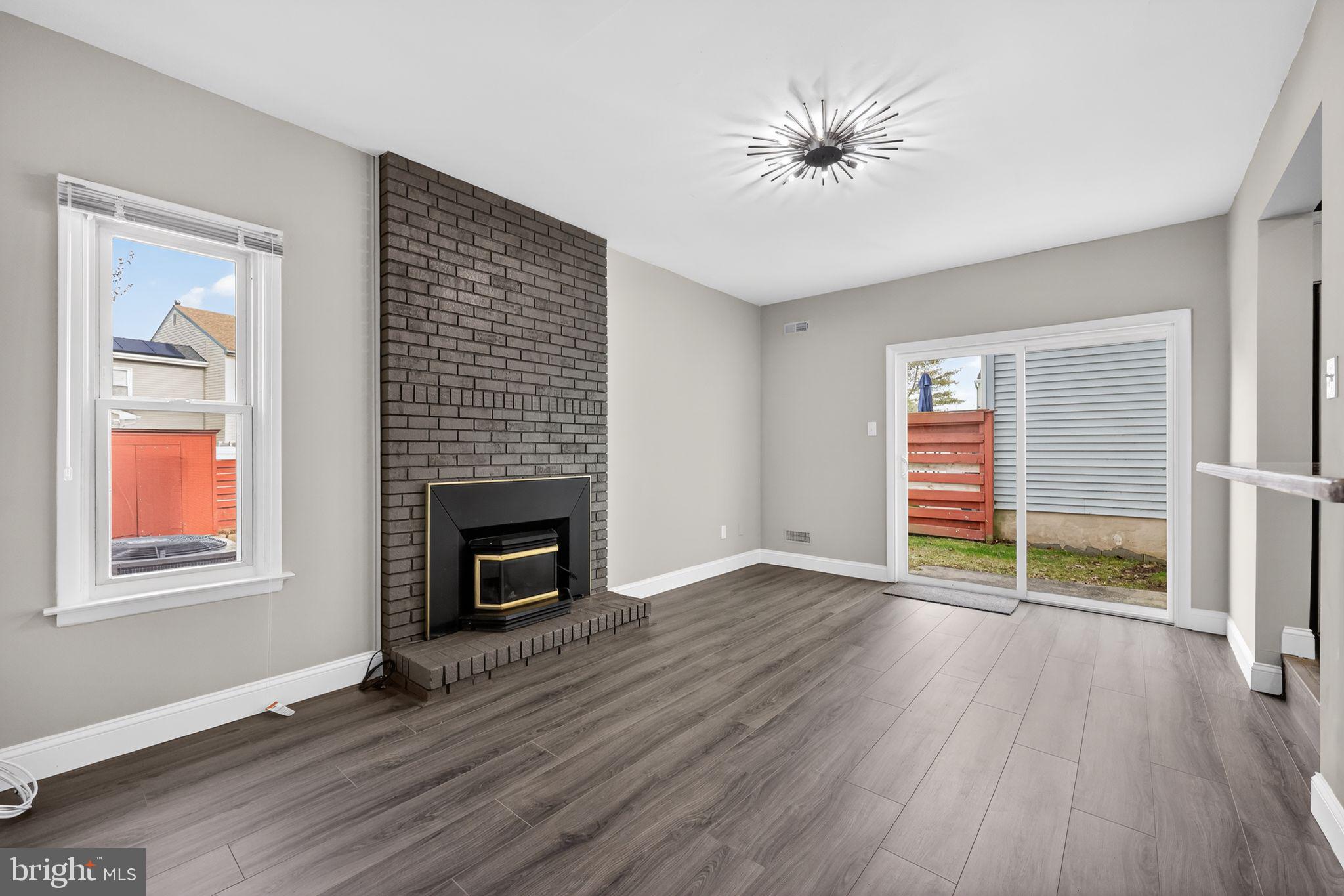 55 Adams Street Swedesboro, NJ 08085 - Photo 10 of 30 an empty room with wooden floor a fireplace and windows