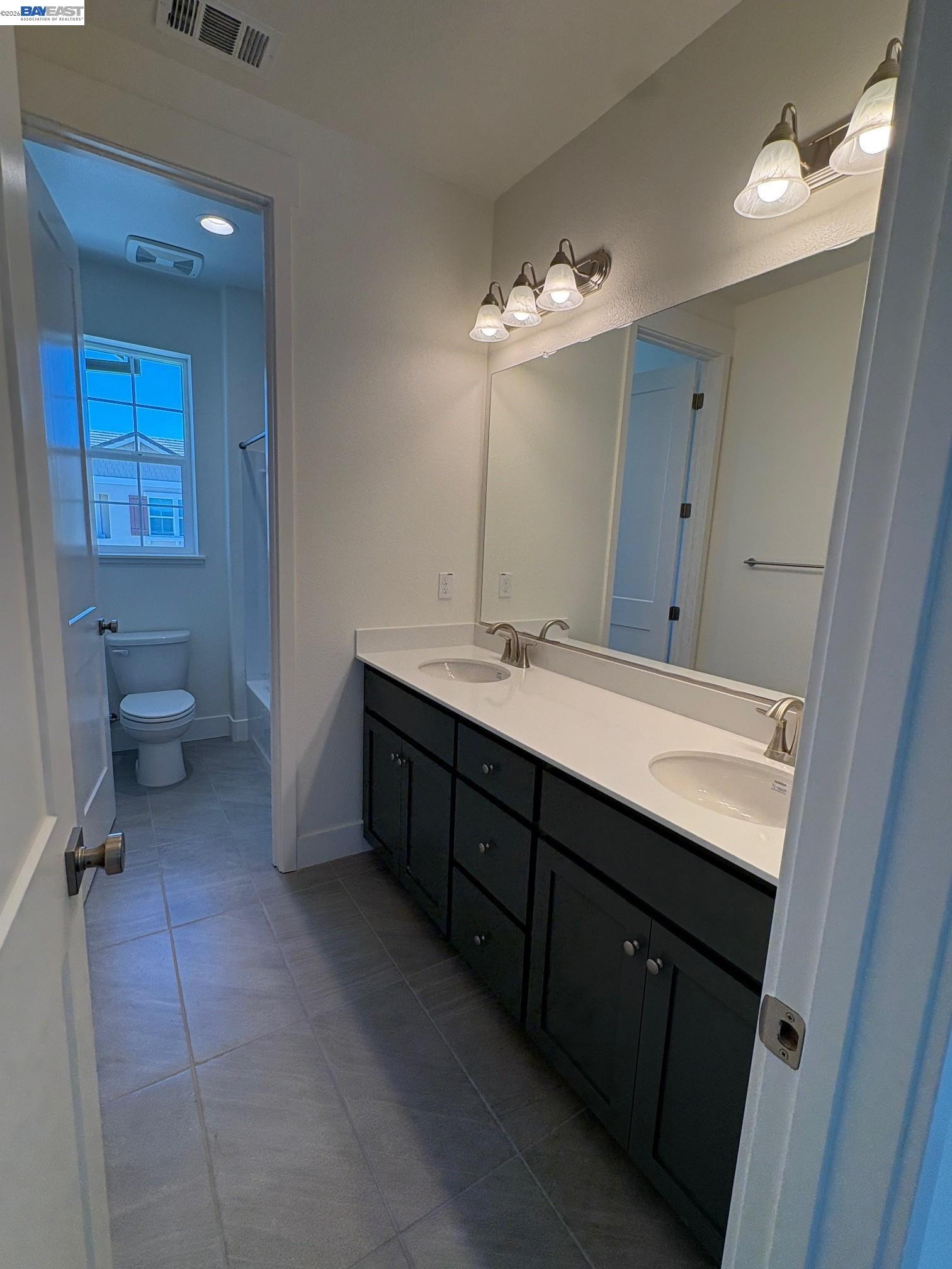 1476 Monument Lane Fairfield, CA 94533 - Photo 17 of 24 a bathroom with a double vanity sink a toilet and a mirror