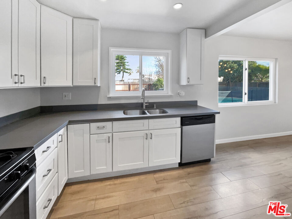 6906 Balcom Avenue Reseda, CA 91335 - Photo 12 of 19 a kitchen with granite countertop white cabinets white appliances a sink and a window