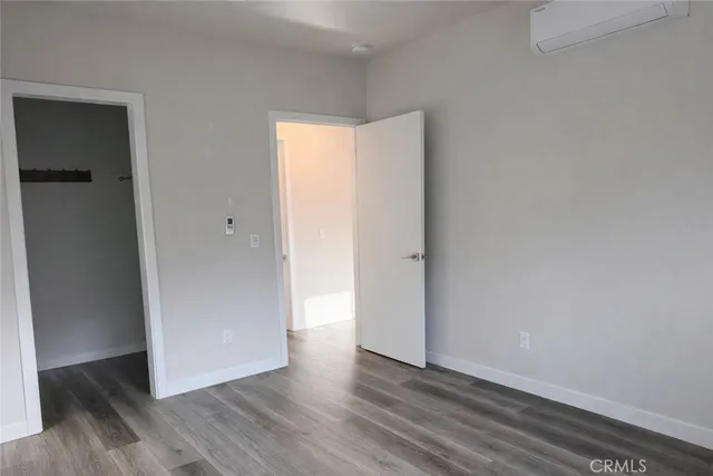 a view of an empty room with wooden floor and closet