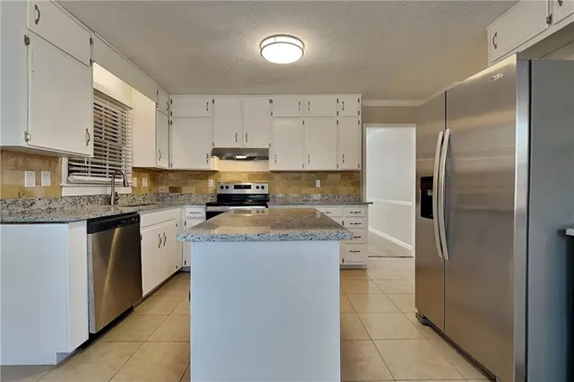a kitchen with stainless steel appliances granite countertop a refrigerator a stove and a sink