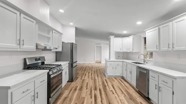 a kitchen with white cabinets sink and stainless steel appliances