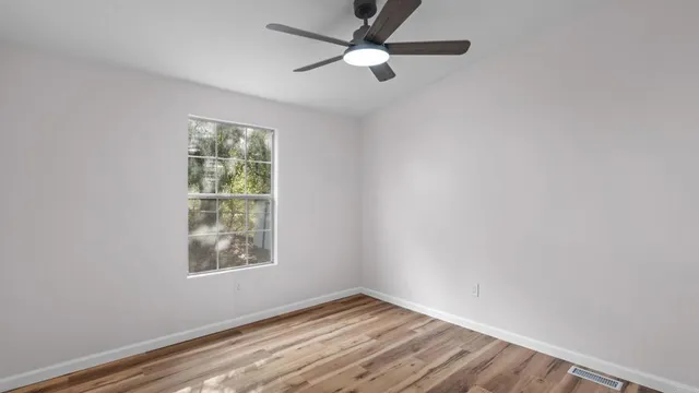 an empty room with windows and fan