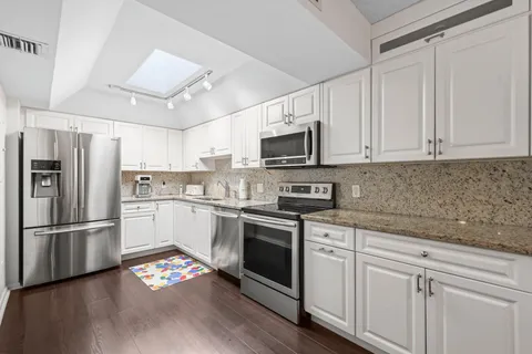 a kitchen with granite countertop white cabinets stainless steel appliances and wooden floor