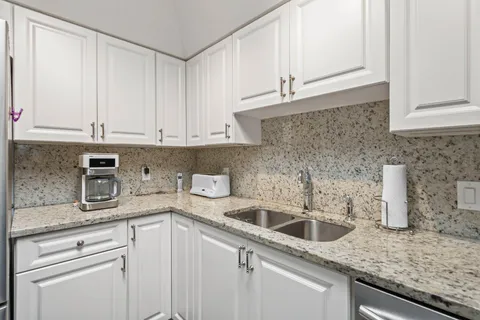 a kitchen with granite countertop white cabinets and a sink