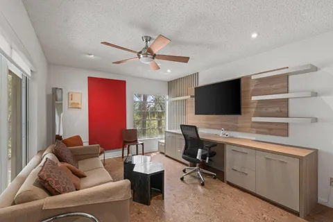 a living room with furniture a ceiling fan and a large window