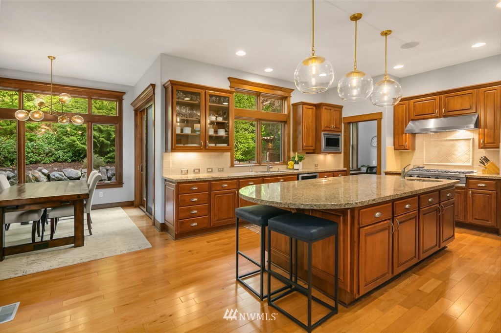 2989 Northeast Davis Loop Issaquah, WA 98029 - Photo 15 of 37 a kitchen with stainless steel appliances granite countertop a stove a sink a refrigerator a dining table and chairs with wooden floor