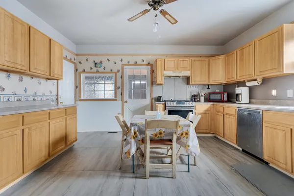 a kitchen with cabinets a sink dishwasher a dining table and chairs with wooden floor