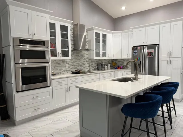 a kitchen with stainless steel appliances kitchen island a table chairs sink and cabinets
