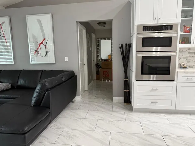 a living room with stainless steel appliances kitchen island granite countertop a stove and a refrigerator