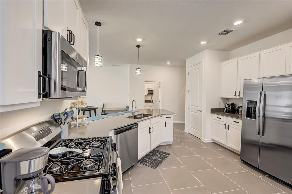 a large kitchen with stainless steel appliances a sink a stove a refrigerator and cabinets