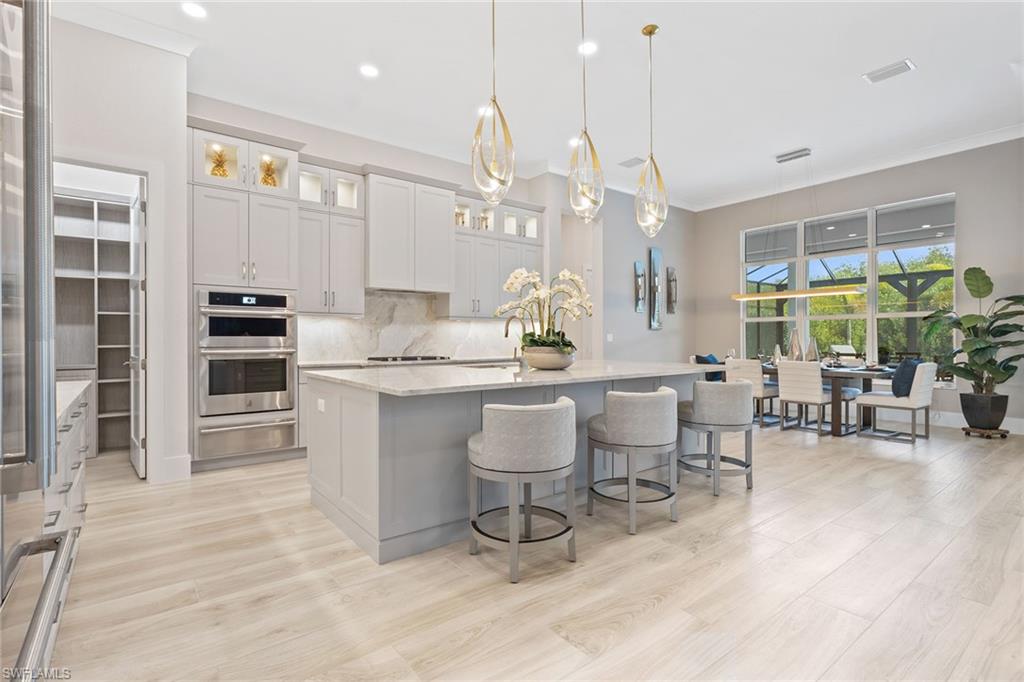 8829 Paradera Court Naples, FL 34112 - Photo 6 of 31 a room with stainless steel appliances kitchen island granite countertop furniture and a view of living room