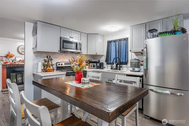 a kitchen with stainless steel appliances granite countertop a refrigerator a sink a stove and white cabinets