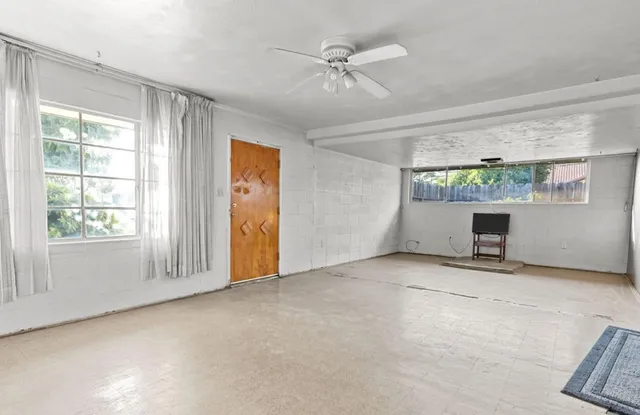 an empty room with windows and a ceiling fan