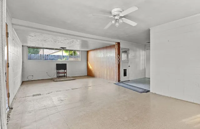 an empty room with a windows and ceiling fan