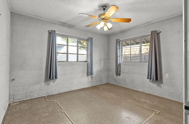 an empty room with windows and a chandelier fan