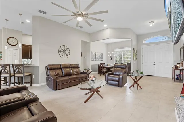 a living room with furniture a clock and a ceiling fan