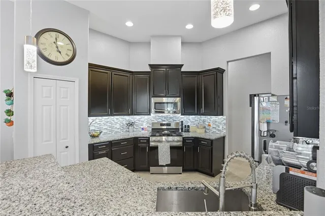 a kitchen with stainless steel appliances kitchen island granite countertop a refrigerator and a stove top oven