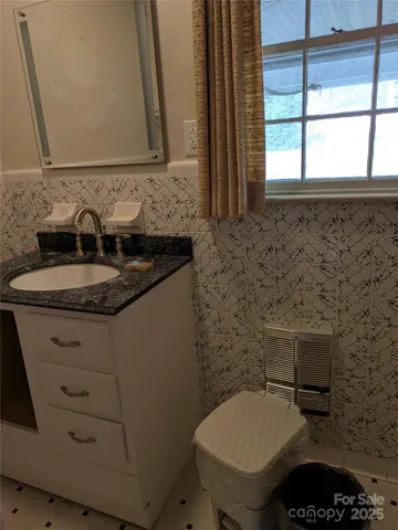 a bathroom with a granite countertop toilet sink and mirror
