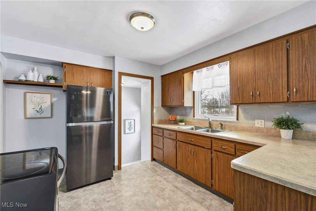 17239 Fowles Road Cleveland, OH 44130 - Photo 12 of 43 Kitchen featuring backsplash, range, sink, and stainless steel refrigerator