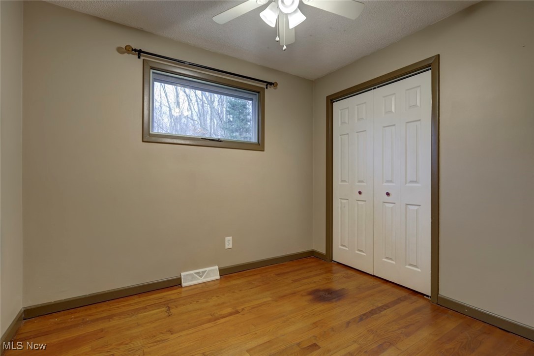 8104 Barnes Road Vermilion, OH 44089 - Photo 25 of 40 Unfurnished bedroom with ceiling fan, light hardwood / wood-style floors, a textured ceiling, and a closet