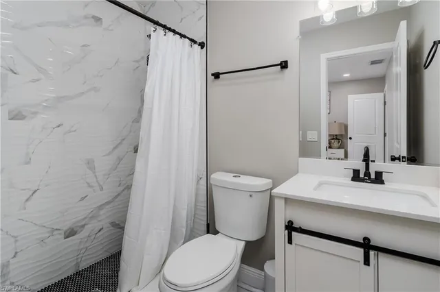 a bathroom with a sink a toilet a mirror and shower