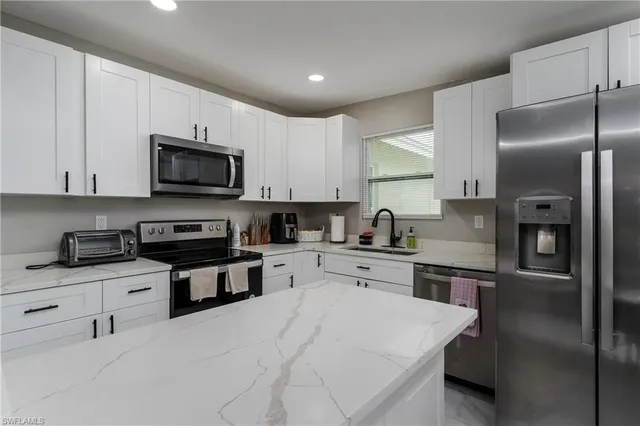 a kitchen with stainless steel appliances granite countertop a refrigerator stove microwave and sink