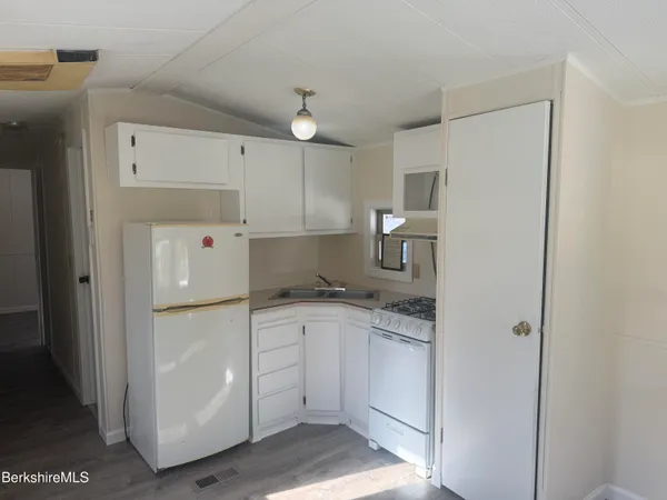 a kitchen with white cabinets and refrigerator