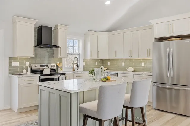 a kitchen with stainless steel appliances a refrigerator a stove a sink dishwasher and white cabinets with wooden floor