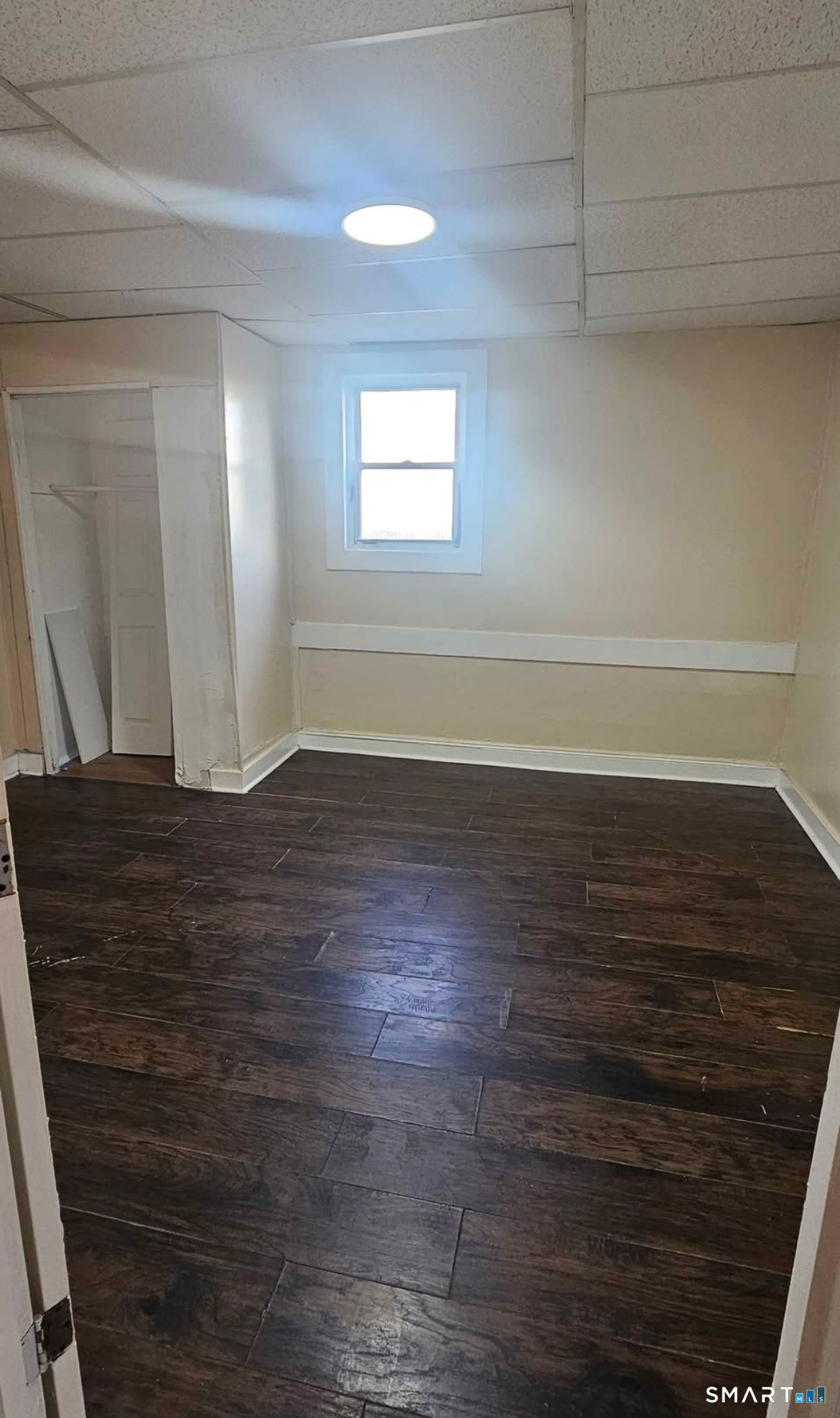 1495 Pembroke Street, Unit 1R Bridgeport, CT 06608 - Photo 5 of 6 a view of an empty room with wooden floor and a window