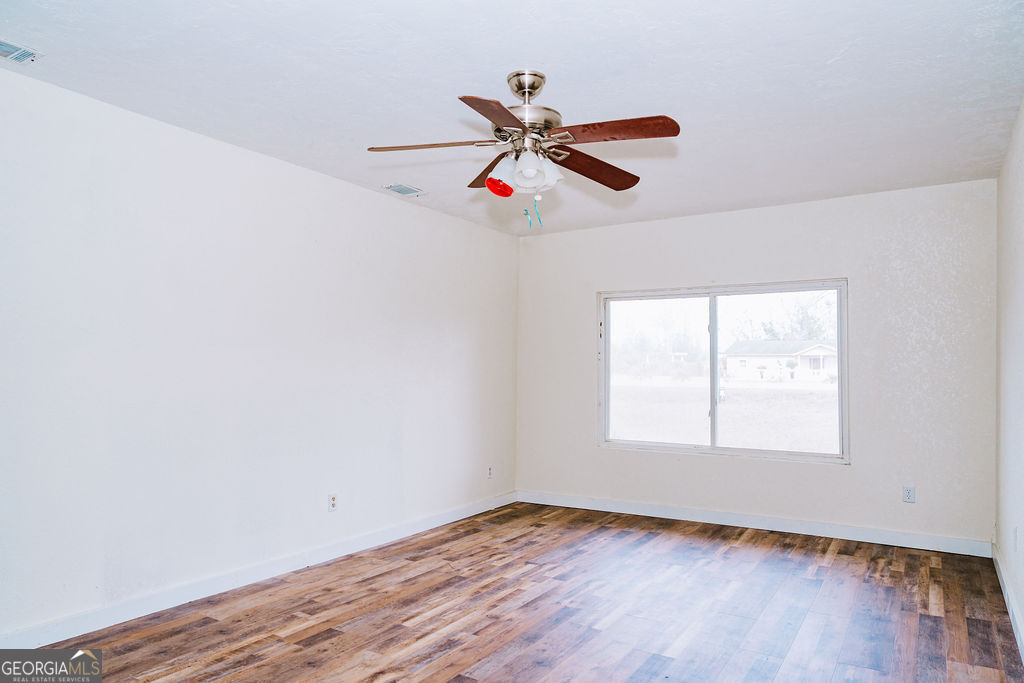 3017 Albany Avenue Waycross, GA 31503 - Photo 22 of 23 an empty room with wooden floor ceiling fan and windows