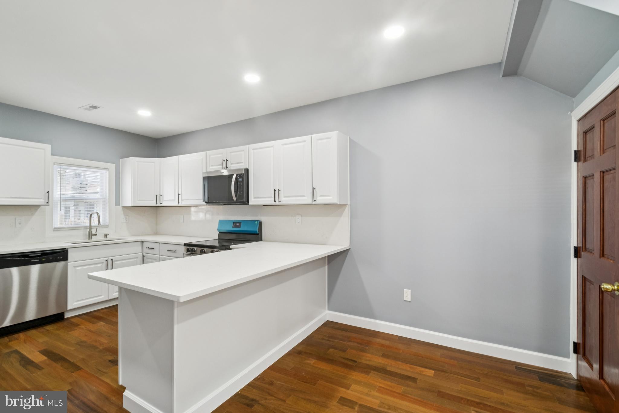 3607 4th Street Baltimore, MD 21225 - Photo 4 of 16 a kitchen with a sink a stove a refrigerator and white cabinets