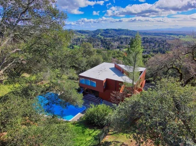 an aerial view of a house with large trees and a yard
