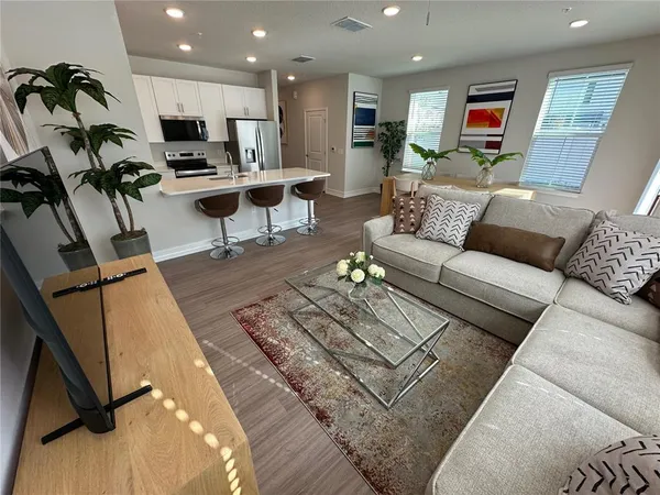a living room with furniture kitchen view and a wooden floor