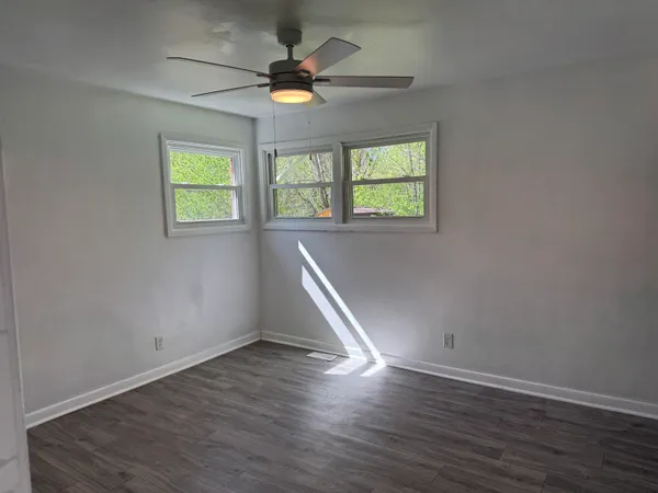 an empty room with wooden floor and windows