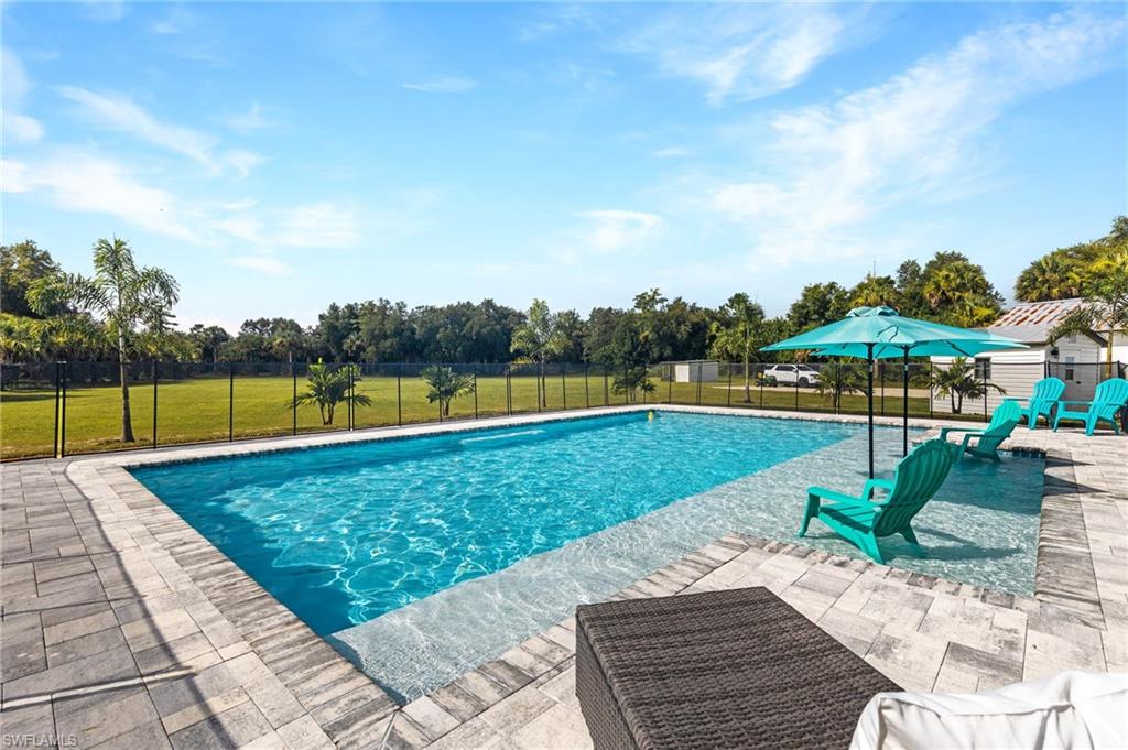 1330 Rock Road Naples, FL 34120 - Photo 1 of 37 View of swimming pool with fence, a fenced in pool, a lawn, and a patio
