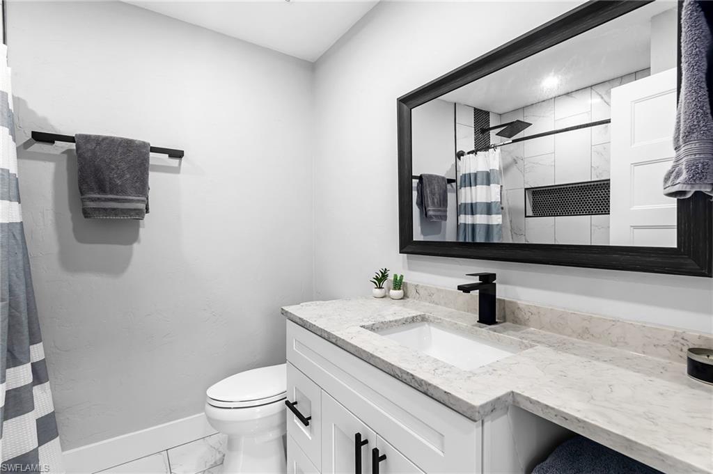 1330 Rock Road Naples, FL 34120 - Photo 18 of 37 Bathroom featuring vanity, toilet, marble finish floor, baseboards, and curtained shower