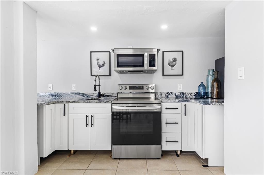 1330 Rock Road Naples, FL 34120 - Photo 32 of 37 Kitchen featuring white cabinets, a sink, stone countertops, stainless steel appliances, and light tile patterned floors