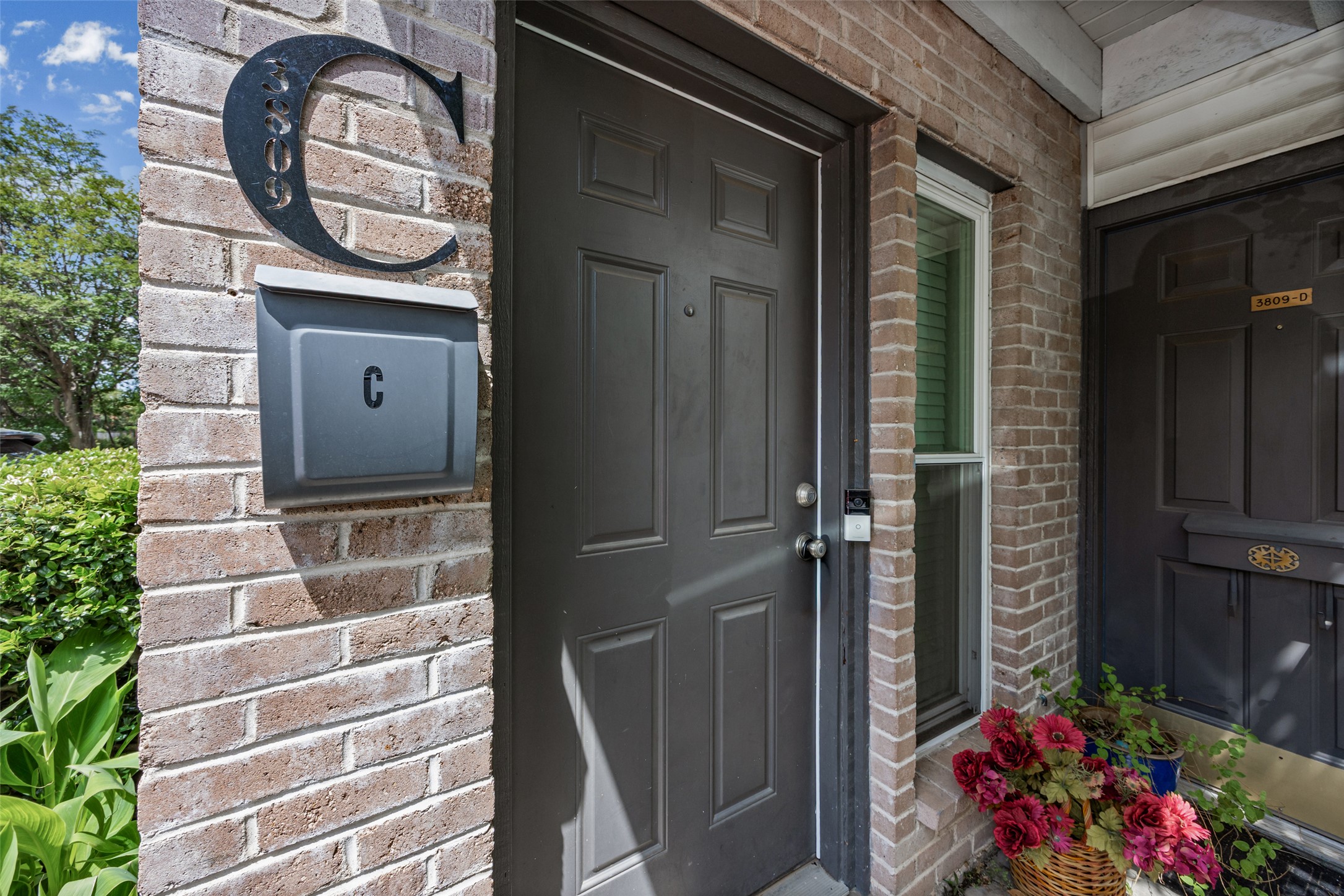 3809 Menchaca Road, Unit C Austin, TX 78704 - Photo 21 of 28 A welcoming brick facade with a dark entry door and vibrant floral accents.