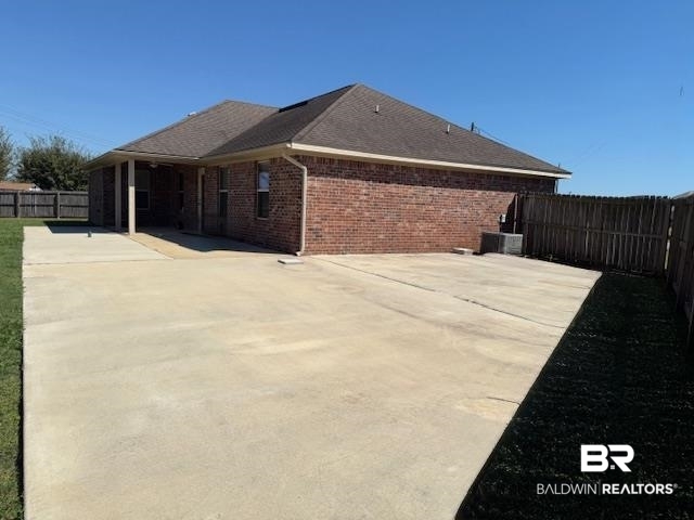 15577 Talus Court Foley, AL 36535 - Photo 18 of 28 View of side of home featuring a fenced backyard, brick siding, roof with shingles, and concrete driveway