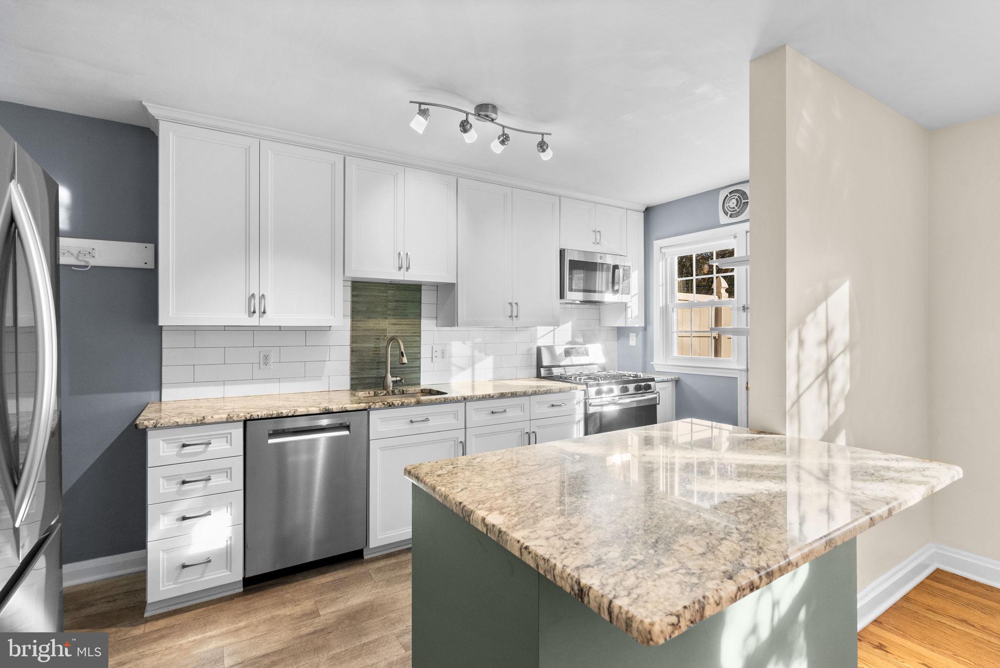 324 Stanmore Road Baltimore, MD 21212 - Photo 12 of 40 a kitchen with stainless steel appliances granite countertop a sink dishwasher and refrigerator with wooden floor