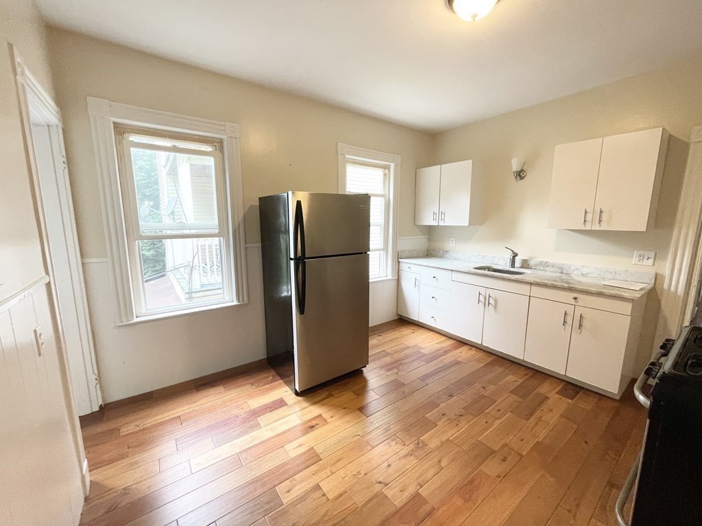 a kitchen with a refrigerator a sink and dishwasher with wooden floor